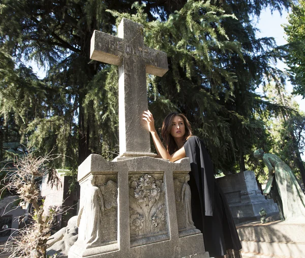 Женский портрет в горе рядом с могильным крестом — стоковое фото