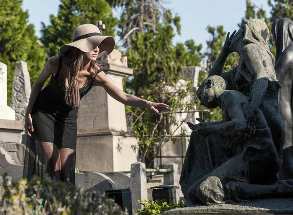 Portrait de femme atteignant des statues dans le cimetière — Photo