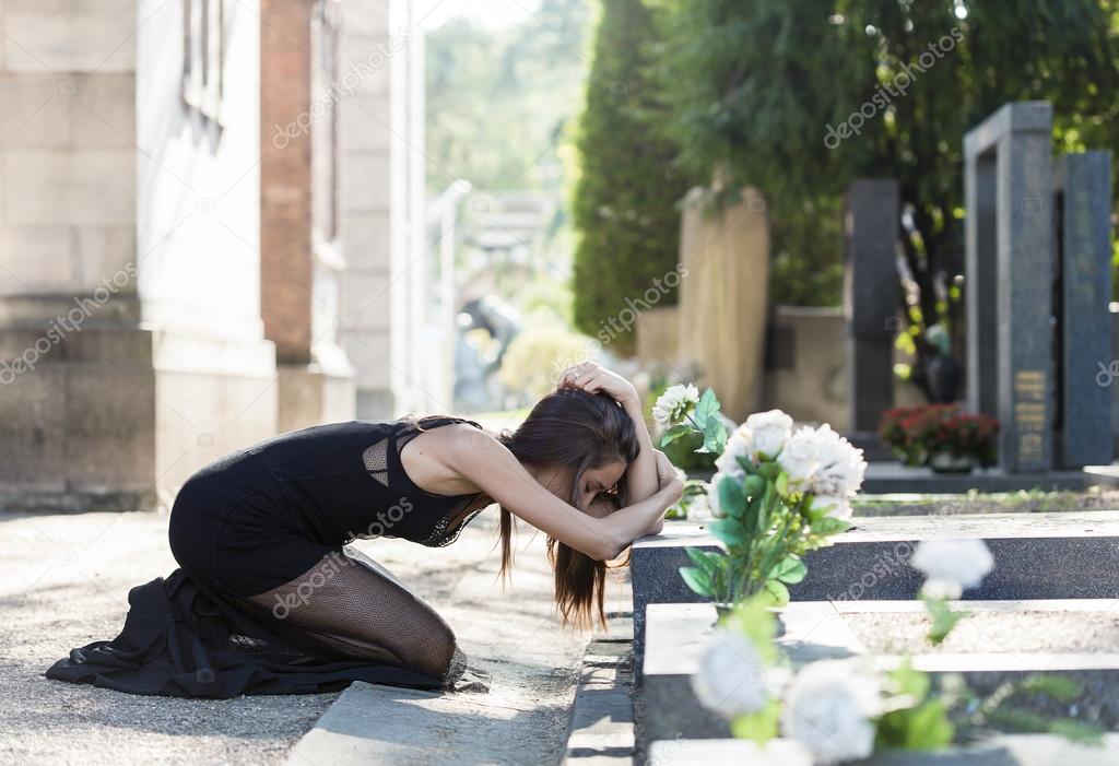 Afflicted woman portrait in grief in front of a grave
