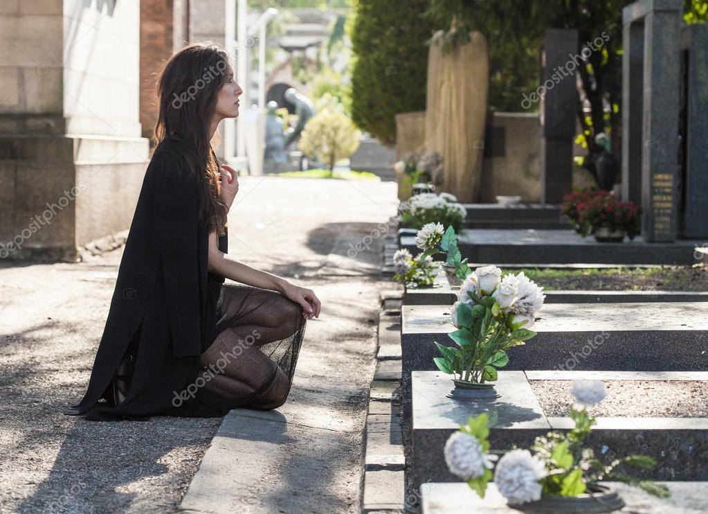 Woman portrait on her knees in front of a grave