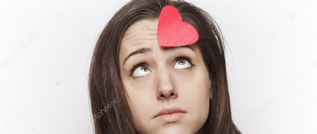 Sad girl looking at paper heart on her forehead letterbox