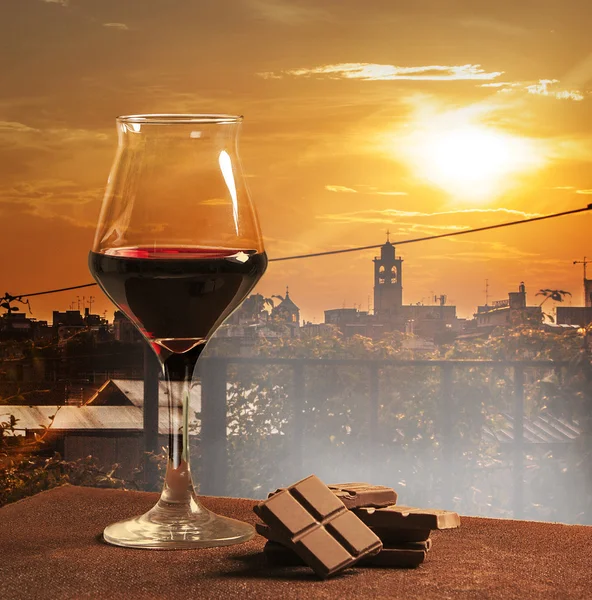 Copa de vino y chocolate con puesta de sol naranja ciudad — Foto de Stock