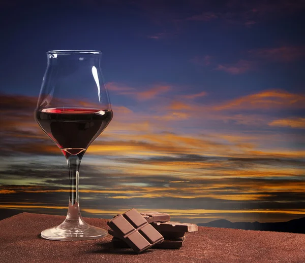 Bicchiere di vino e cioccolato con tramonto colorato — Foto Stock