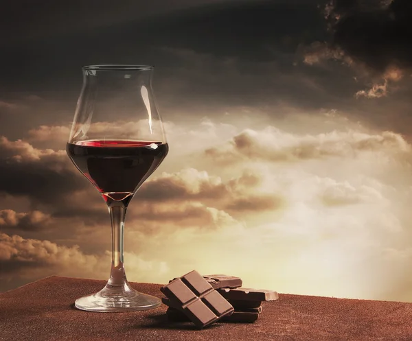 Glas vin och choklad med orange solnedgång molnlandskap — Stockfoto