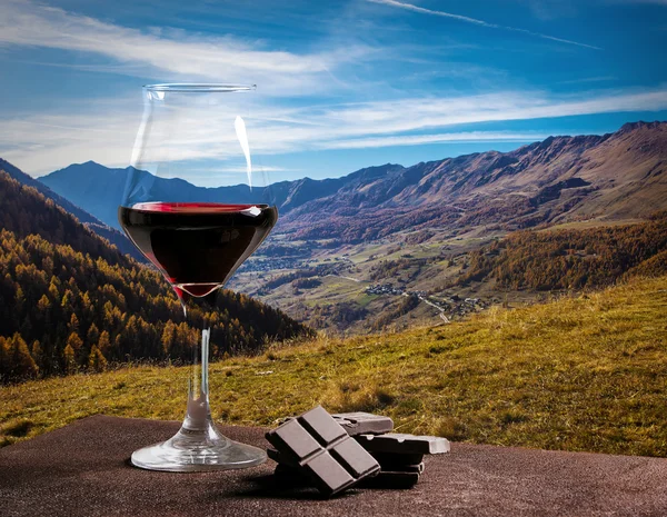 Ποτήρι κόκκινο κρασί και σοκολάτα με το πανέμορφο τοπίο του φθινοπώρου — Φωτογραφία Αρχείου