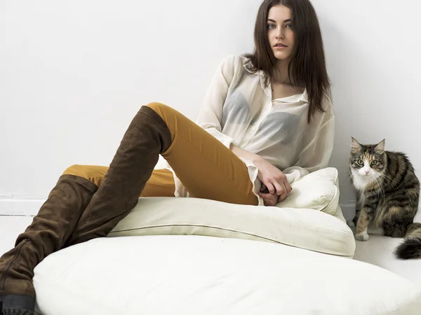 Jolie fille portrait assis sur des coussins et regarder et chat — Photo