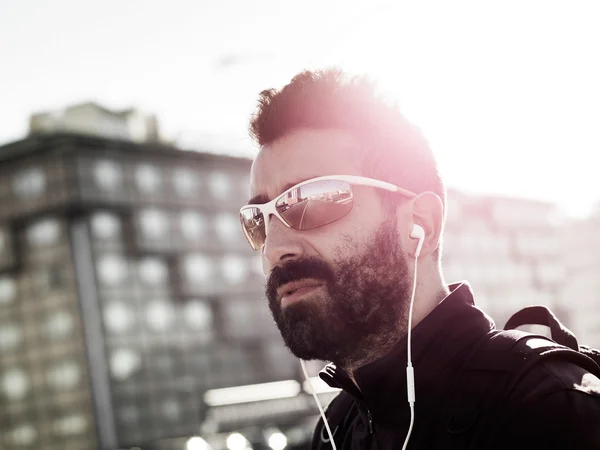Retrato de deportista guapo en la ciudad con gafas de sol y — Foto de Stock