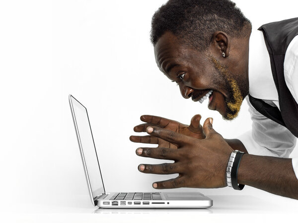 Веселый африканский портрет бизнесмена, работающего за ноутбуком
