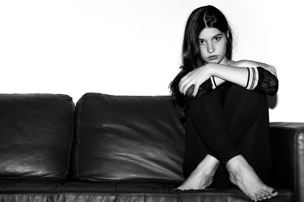 Portrét dívky sedí na pohovce černá a bílá — Stock fotografie