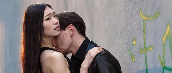 Man wearing leather coat hugging girlfriend in the city letterbo — Stock Photo, Image