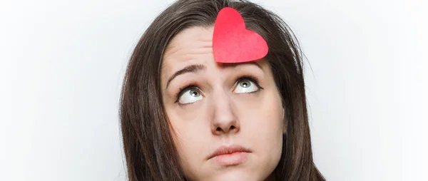 Sad girl looking at paper heart on her forehead letterbox — Stock Photo, Image