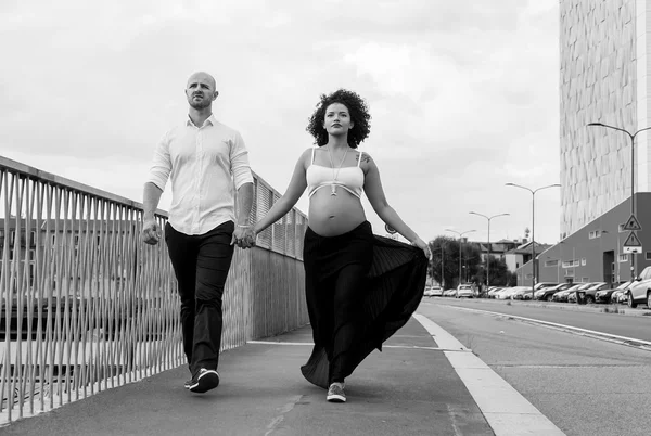 Beautiful pregnant couple walking hand in hand black and white — Stock Photo, Image