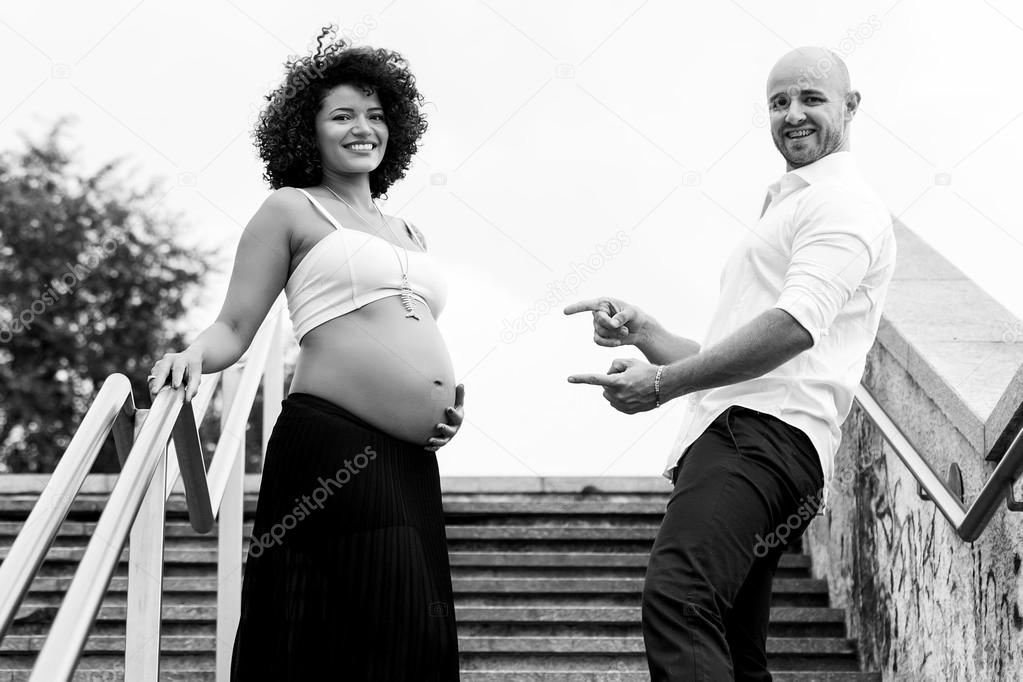 Pregnant couple portrait on the stairs in the city monochrome