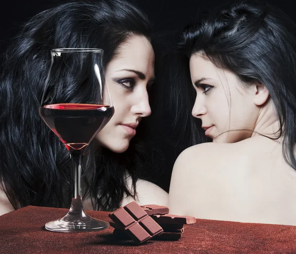 Copa de vino tinto y chocolate con chicas mirándose — Foto de Stock