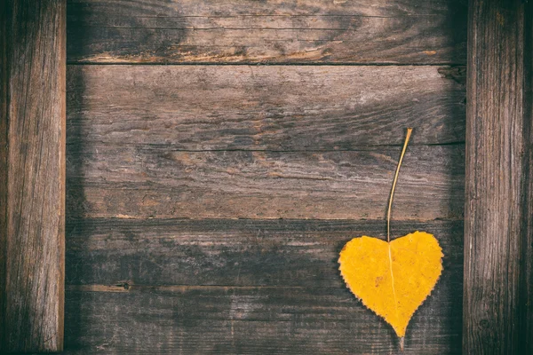 Желтый лист в виде сердца на деревянном фоне. Осенний фон — стоковое фото