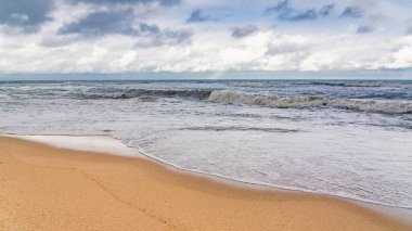Boş sahil ve bulutlu havada fırtınalı deniz