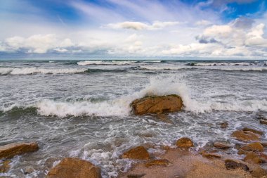 Boş sahil ve bulutlu havada fırtınalı deniz