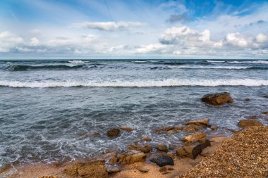 Boş sahil ve bulutlu havada fırtınalı deniz