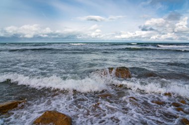 Boş sahil ve bulutlu havada fırtınalı deniz