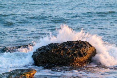 Büyük taş ve dalgalar deniz kıyısına vuruyor.