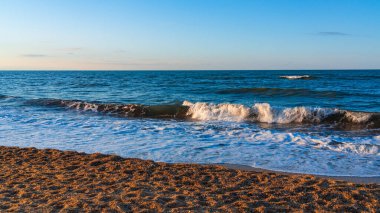 Sarı kumlu ve mavi dalgalı boş sahil, tatil köyünde karantina.