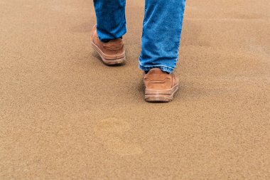 Bir adam kumda yürüyor.