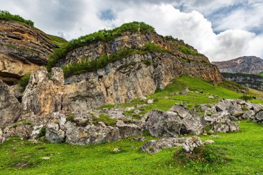 Dağlık arazide yeşil bir çayırdaki kayaların parçaları.