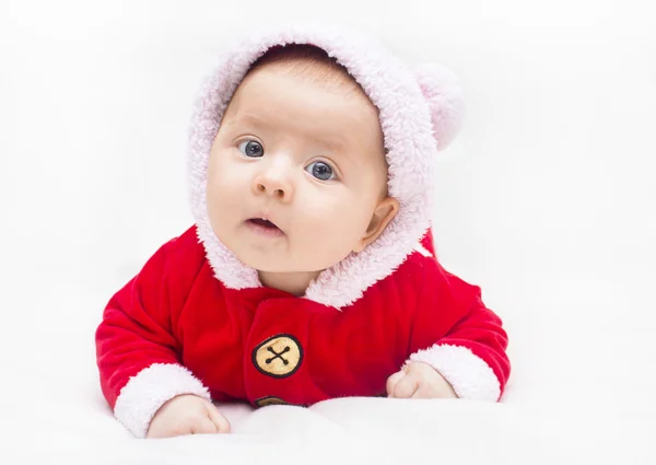 Glada barnet ligger på mage bär en röd och vit jul Santa sui — Stockfoto