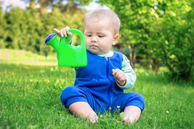 Ca sulama ile parkta çimlere oturup şirin bebek