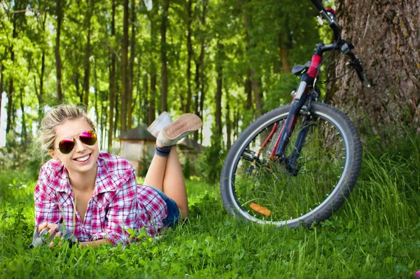 Junge Radfahrerin entspannt im Gras liegend — Stockfoto