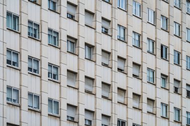 Bir şehir binasının ön cephesinde tekerlekli panjurları olan sıra sıra pencereler