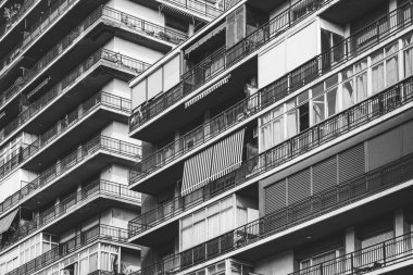 Siyah beyaz iki konut binasının cephelerinde sıra sıra balkonlar.