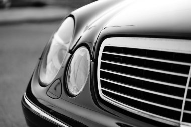 Siyah beyaz şık bir arabanın ızgarası ve farları.