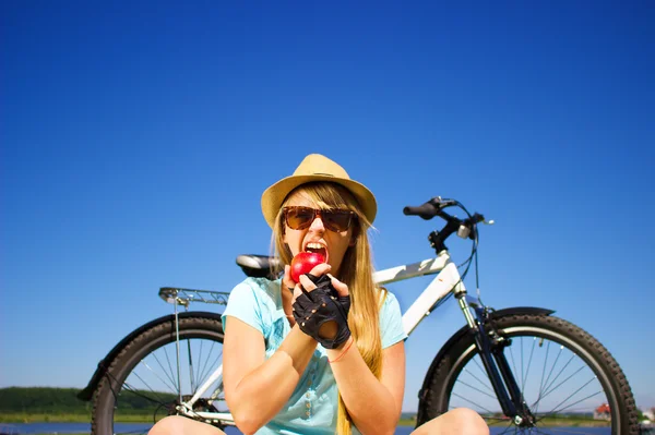 Glückliche junge Frau mit Apfel entspannt sich nach dem Radfahren — Stockfoto