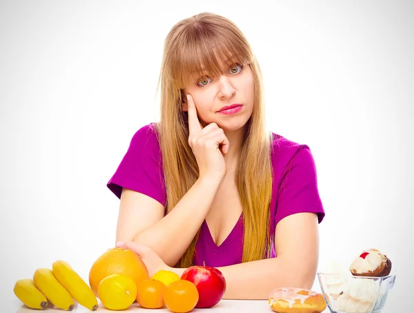 Жінка вибирає між фруктами і цукерками — стокове фото