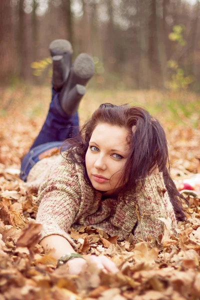 年轻女子躺在秋天的落叶 — 图库照片