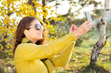Selfie sonbahar günü parkta alarak genç güzel kadın