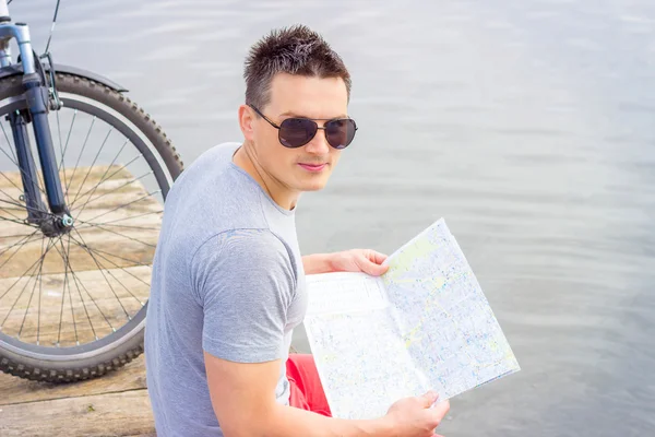 young man, one happy tourist bicyclist with route map wearing in gray shirt with glasses