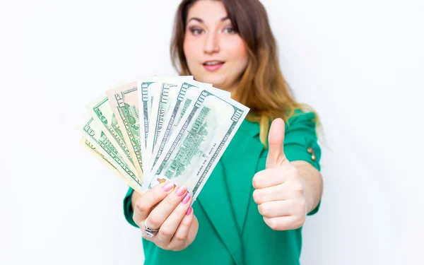 Feliz mujer de negocios sonriente vistiendo chaqueta verde con los pulgares hacia arriba gesto y dinero. Primer plano retrato super feliz emocionado exitosa joven mujer de negocios con billetes de dólar de dinero —  Fotos de Stock