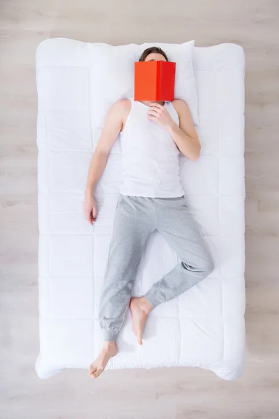 Sleeping man lying in bed with book — Stock Photo, Image