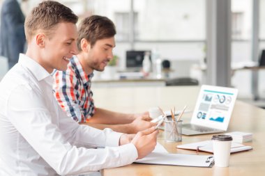 Cep telefonlarını tutan neşeli erkekler