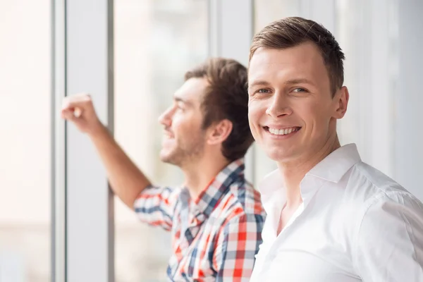 Contenido sonriente hombre de pie cerca de la ventana —  Fotos de Stock