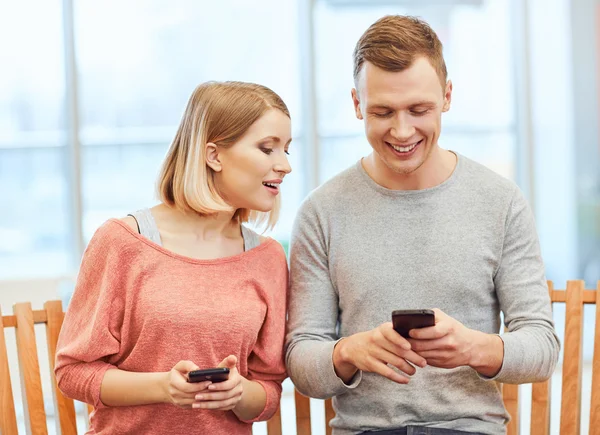 Pleasant girl and boy using smart phones — Stock Photo, Image