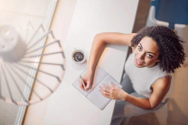 Chica positiva sentada en la mesa . — Foto de Stock