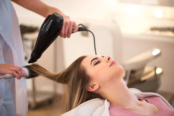 Parrucchiere professionista asciugando i capelli del suo cliente — Foto Stock