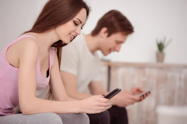 Joli jeune couple utilisant des téléphones cellulaires — Photo