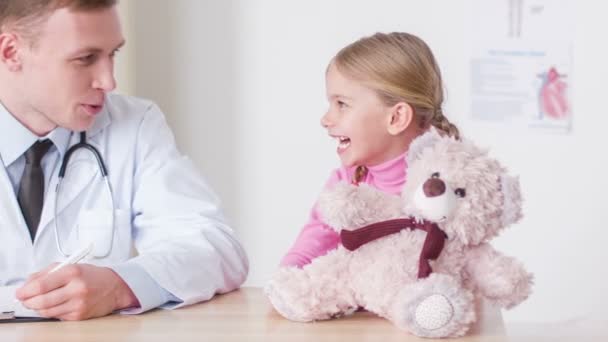 Профессиональный врач разговаривает с маленькой девочкой — стоковое видео