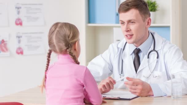 Médico positivo examinando a una niña — Vídeo de stock