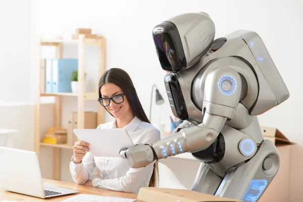 Приємна дівчина і робот, що працює в офісі — стокове фото
