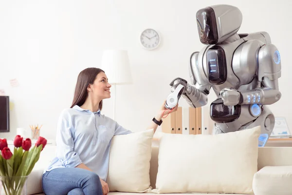 Chica positiva dando auriculares a robot moderno —  Fotos de Stock
